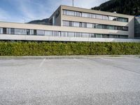 a building sits in a parking lot surrounded by hedges and mountain ranges on the horizon