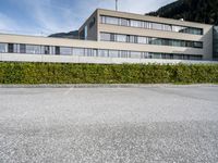 a building sits in a parking lot surrounded by hedges and mountain ranges on the horizon