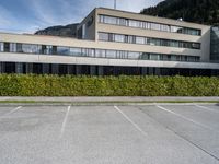 a building sits in a parking lot surrounded by hedges and mountain ranges on the horizon