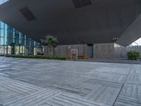 some empty area with grey tiled floor and wooden benches outside an open area with large windows