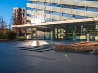 an open courtyard area has green grass, trees, and buildings on the other side