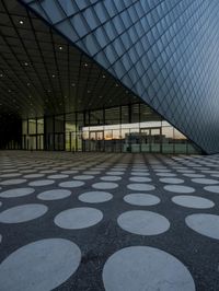 the inside of an office building with large windows and circular spots on a concrete surface