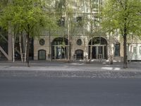 a building with some chairs under it next to the street where there are some trees