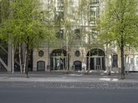 a building with some chairs under it next to the street where there are some trees