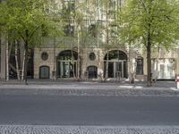a building with some chairs under it next to the street where there are some trees