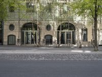 a building with some chairs under it next to the street where there are some trees