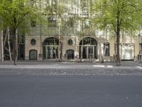 a building with some chairs under it next to the street where there are some trees