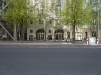 a building with some chairs under it next to the street where there are some trees