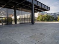 an empty concrete surface with glass walls and an open space in the background with trees in the distance