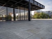 an empty concrete surface with glass walls and an open space in the background with trees in the distance