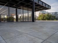 an empty concrete surface with glass walls and an open space in the background with trees in the distance