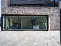 a modern brick building with an external glass door and brick facade next to a sidewalk