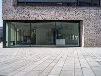 a modern brick building with an external glass door and brick facade next to a sidewalk