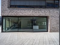 a modern brick building with an external glass door and brick facade next to a sidewalk