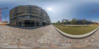 a circular photo of a modern office building on the edge of a brick road with a construction crane