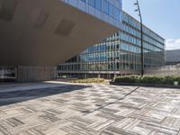 a sidewalk outside with an open space in the foreground that has a building and large mirrored windows