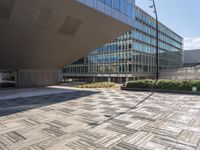 a sidewalk outside with an open space in the foreground that has a building and large mirrored windows