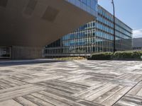 a sidewalk outside with an open space in the foreground that has a building and large mirrored windows