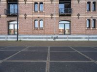 two buildings with windows and a skateboard in front of it on a concrete ground