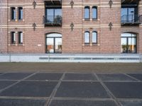 two buildings with windows and a skateboard in front of it on a concrete ground