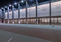 a large building with several glass windows and some lights above it with one light on in the middle