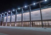 a large building with several glass windows and some lights above it with one light on in the middle