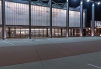 a large building with several glass windows and some lights above it with one light on in the middle