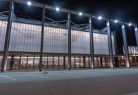 a large building with several glass windows and some lights above it with one light on in the middle