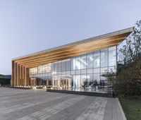 large, modern office building with a wooden structure at twilight with a blue sky behind it