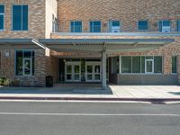 the front of a building with a building awning in the middle and a sidewalk outside of the building