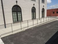 there is a building with metal railing on it near street and building side walk, in the background