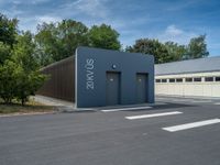 a metal building with a corrugated door in front of it and trees lining the street behind it