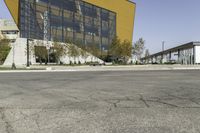 empty asphalt street with a building next to it in front of a building with many windows