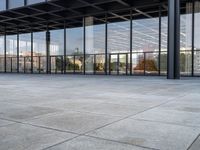 a tiled floor outside a large building with multiple windows and lots of glass in it