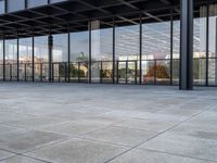 a tiled floor outside a large building with multiple windows and lots of glass in it