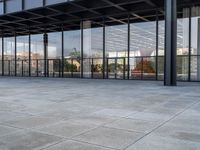 a tiled floor outside a large building with multiple windows and lots of glass in it