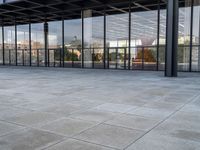 a tiled floor outside a large building with multiple windows and lots of glass in it