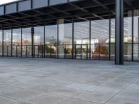 a tiled floor outside a large building with multiple windows and lots of glass in it