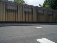 a metal building with a corrugated door in front of it and trees lining the street behind it