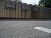 a metal building with a corrugated door in front of it and trees lining the street behind it