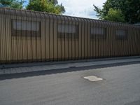 a metal building with a corrugated door in front of it and trees lining the street behind it