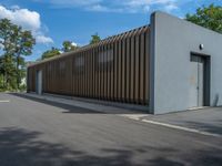 a metal building with a corrugated door in front of it and trees lining the street behind it