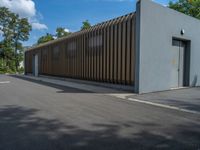 a metal building with a corrugated door in front of it and trees lining the street behind it