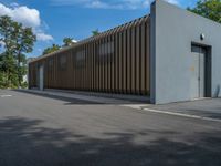 a metal building with a corrugated door in front of it and trees lining the street behind it