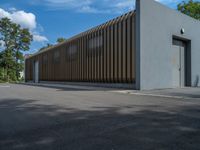 a metal building with a corrugated door in front of it and trees lining the street behind it