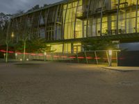 an office building with a gated area and a fence surrounding by it, at twilight