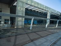 the outside of an airport terminal with concrete steps and glass doors, alongside it is covered in white mesh