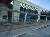 the outside of an airport terminal with concrete steps and glass doors, alongside it is covered in white mesh