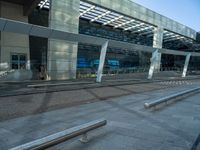 the outside of an airport terminal with concrete steps and glass doors, alongside it is covered in white mesh