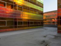 an orange yellow and green building next to each other on top of a road under a clear blue sky